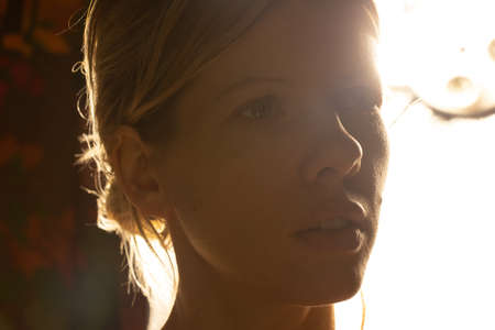 portrait of a young girl in a dark room against the background of a bright lampの写真素材