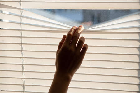 finger on the blinds on the window of the house, look out the window through the blinds from the houseの写真素材