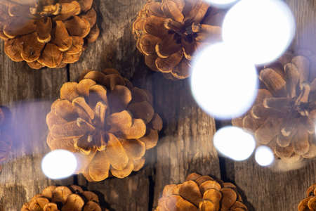 many pine cones on a wooden table against the background of garlands, New Year's decor