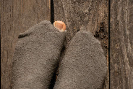 a woman's toe came out of a torn sock on the floor of the house close-up, female feet on the floorの写真素材