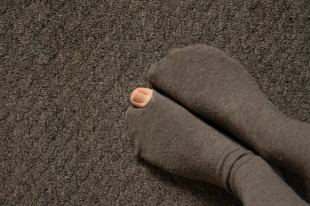 a woman's toe came out of a torn sock on the floor of the house close-up, female feet on the floorの写真素材