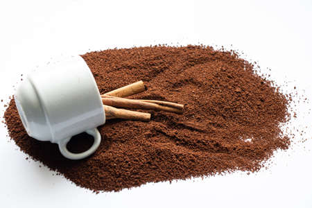 white cup with sprinkled ground coffee and cinnamon on a white background close-upの写真素材