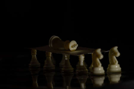 white chess pieces on a board on a black background, playing chessの写真素材