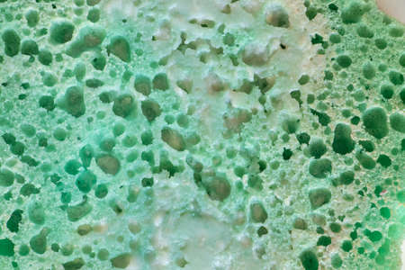 green sponge for bathing in foam as background close-upの写真素材