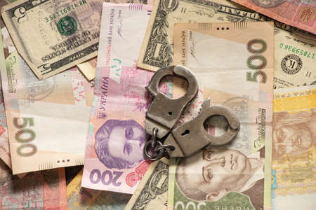 500 and 200 Ukrainian hryvnias lie in the background and are handcuffed on topの写真素材