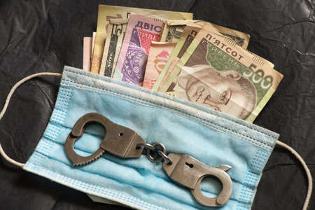 money iron handcuffs and medical mask on isolated background, corruption in medicine