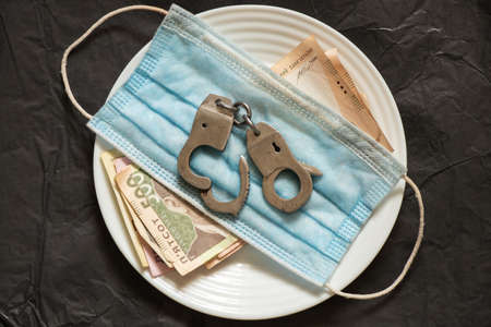 money iron handcuffs and medical mask on isolated background, corruption in medicine