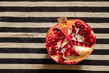 cut half a pomegranate on a striped black and white background close upの写真素材