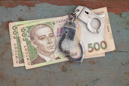 handcuffs lie on a 500 hryvnia bill on a wooden table in the street