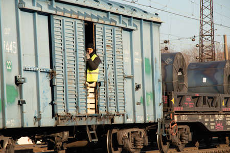 Ukraine Dnipro 07.12.2020 - a man looks out of a freight car of a moving freight train, a railway worker in a train carのeditorial素材