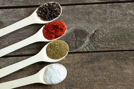 wooden spoons with different types of spices and peppers on a wooden background close-up