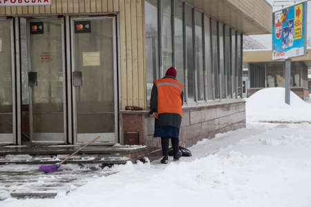 Ukraine Dnipro 13.01.2021 - woman cleans the road from snow in January in a residential area of the cityのeditorial素材