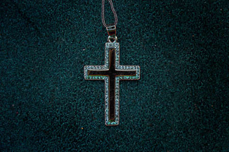 silver cross on a dark green background in neon light close up, faith and riligia