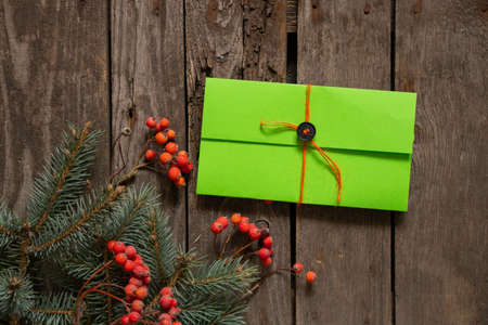 pine branch and viburnum and green envelope with a gift lie on an old wooden background, New Year's decorの写真素材