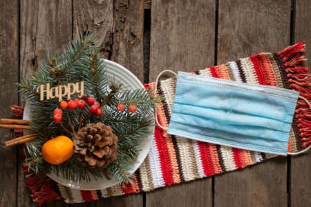 pine branch and viburnum and and a medical mask on a white plate, New Year's decor on the table during the holidays on the pictureの写真素材