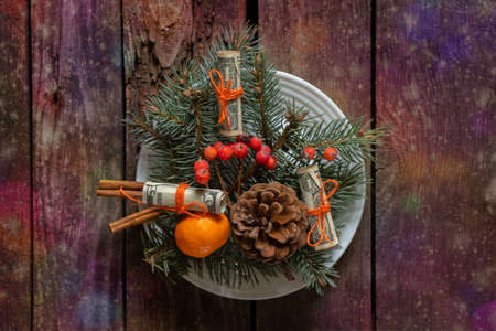 wreath with christmas tree tangerine pine cone and rolled dollar bill on wooden background, new year gift in multicolored lightsの写真素材