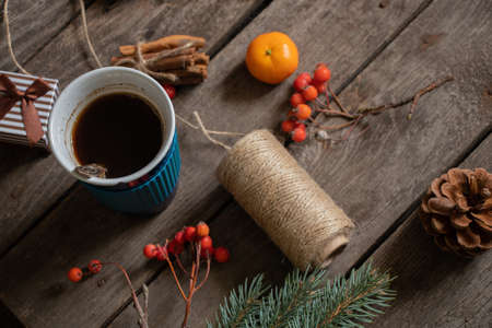 cup with coffee next to a branch of a christmas tree tangerine cinnamon on a wooden table, christmas table with coffee in the morningの写真素材