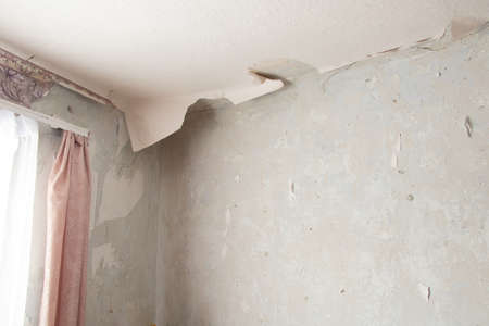 removing old paper wallpaper from the wall in a room of a residential building, renovating an apartmentの写真素材