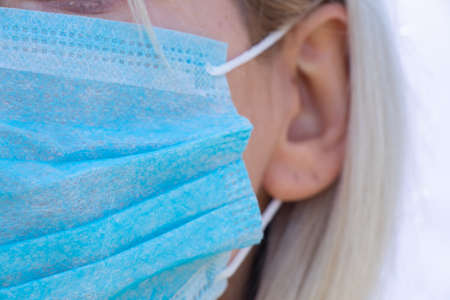 closeup of a young Ukrainian woman in a medical mask on her face during the pandemic outdoorsの写真素材