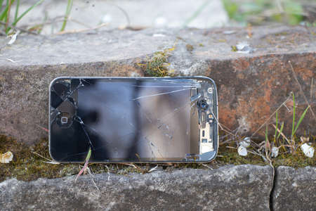 Ukraine, Dnipro - April 03, 2020. An old broken iPhone 4 lies on a stone. Ukraine, Dnipro - April 03, 2020. An old broken iPhone 4 lies on a stone close-up.のeditorial素材