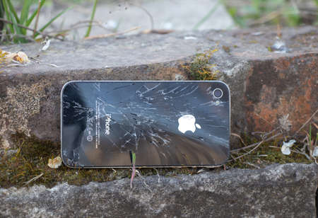 Ukraine, Dnipro - April 03, 2020. An old broken iPhone 4 lies on a stone. Ukraine, Dnipro - April 03, 2020. An old broken iPhone 4 lies on a stone close-up.のeditorial素材