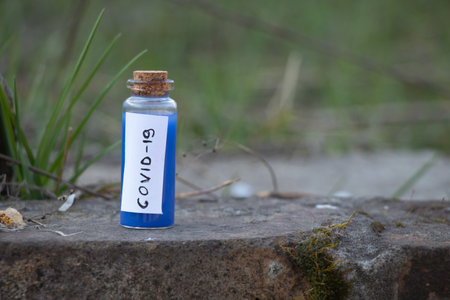 glass test tube with a label and the inscription covid-19 on it on an isolated background close-upの写真素材