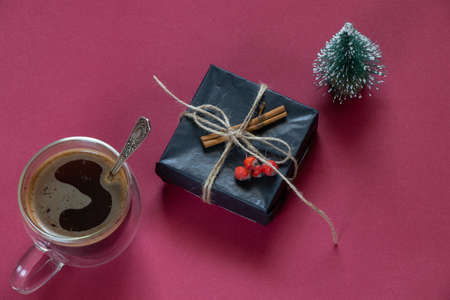box with a gift decorative small Christmas tree and a cup with coffee on a red background, New Year's decorの写真素材