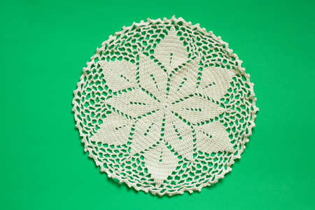 light knitted round lace doily on a green background close-upの写真素材