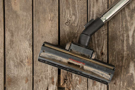 a dirty brush of the vacuum cleaner lies on the wooden floor close-upの写真素材