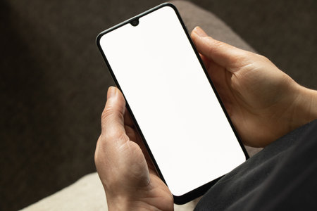 phone in the hands of a young girl with a white screen for design close upの写真素材