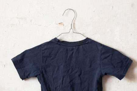 dark blue t-shirt on hangers on an old white wall like moketの写真素材