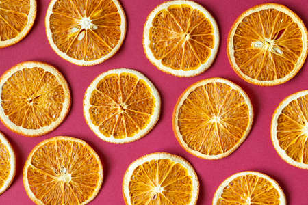 dried orange lies cut into slices on a red background as a background, citrus backgroundの写真素材