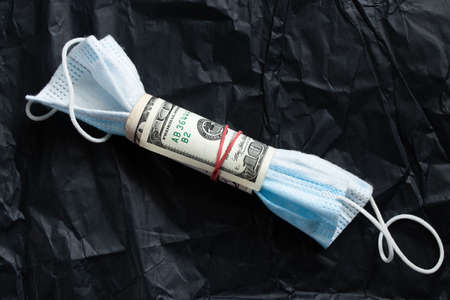 medical mask wrapped with american dollars on an isolated background, medicine and financeの写真素材
