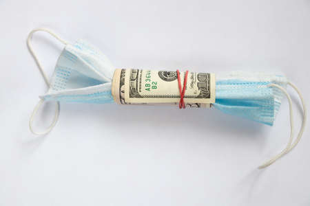 medical mask wrapped with american dollars on an isolated background, medicine and financeの写真素材