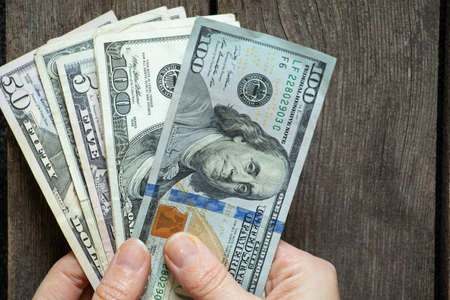 female hands hold american dollars on wooden background close up