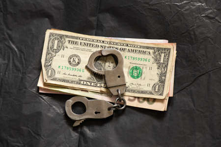 handcuffs on american dollars on a black background, corruption and financeの写真素材