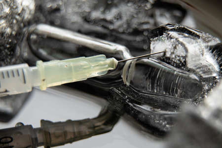 a syringe with a needle and an ampoule with a vaccine in ice, mass vaccination in a pandaの写真素材