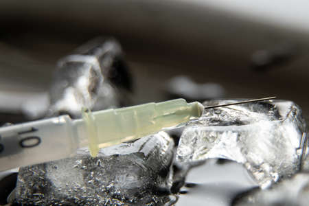 a syringe with a needle and an ampoule with a vaccine in ice, mass vaccination in a pandaの写真素材