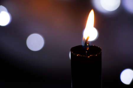 candle flame in the dark on the background of blurry garlands bokeh, religionの写真素材