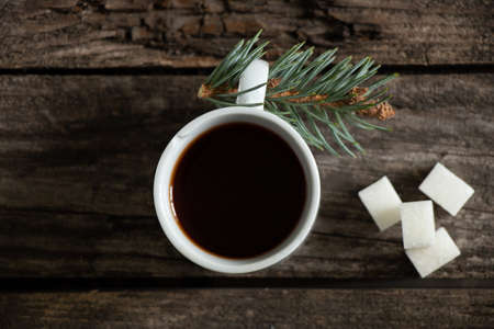 a cup of coffee and a nearby pine branch on a wooden background, new year decorの写真素材