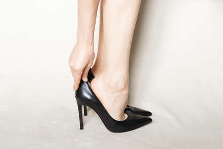 young girl in black pointed toe high-heeled shoes stands on a white carpet at homeの写真素材