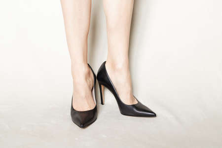 young girl in black pointed toe high-heeled shoes stands on a white carpet at homeの写真素材