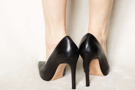 young girl in black pointed toe high-heeled shoes stands on a white carpet at homeの写真素材
