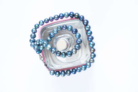 women's perfume and pearl beads on a white background, eau de toilette