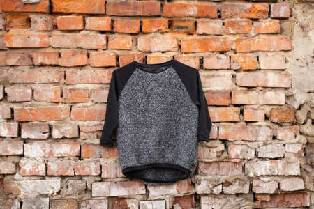 black gray women's blouse hanging on a brick old wall outside in the sunの写真素材
