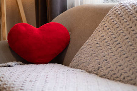 gray sofa and on it a pillow in the shape of a red heart in an apartmentの写真素材
