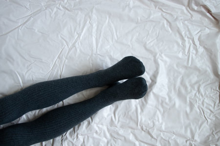 female legs in gray warm tights on a light crumpled backgroundの写真素材
