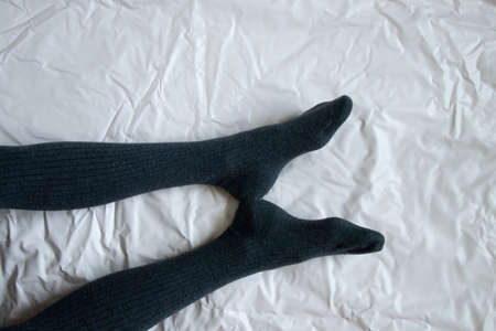 female legs in gray warm tights on a light crumpled backgroundの写真素材