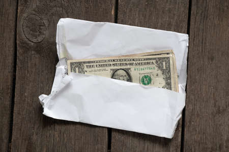 american dollars in a white envelope on an old wooden table close-upの写真素材