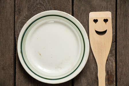 old empty glass white crockery and wooden spatula with a smile on a wooden table, kitchen utensilsの写真素材